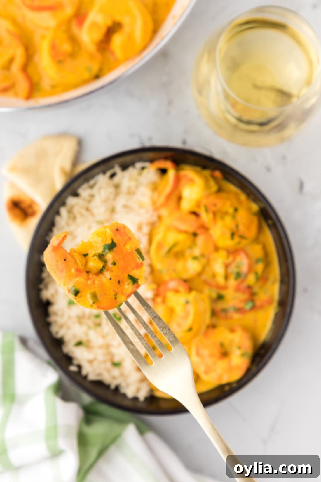 Shrimp Curry on a fork held above a bowl of Shrimp Curry with rice