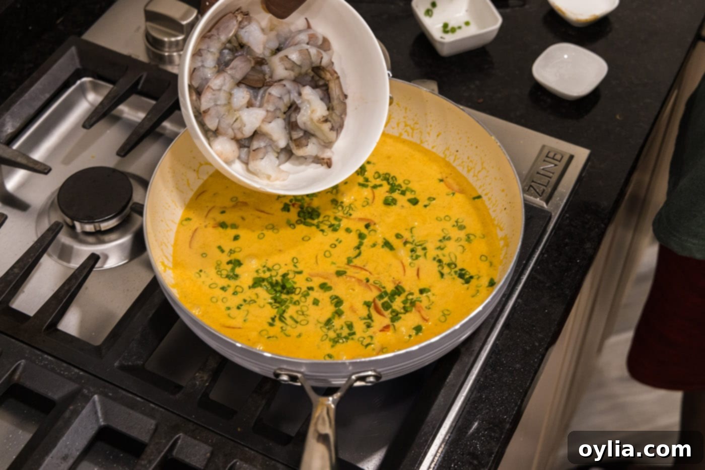 adding raw shrimp into skillet with curry