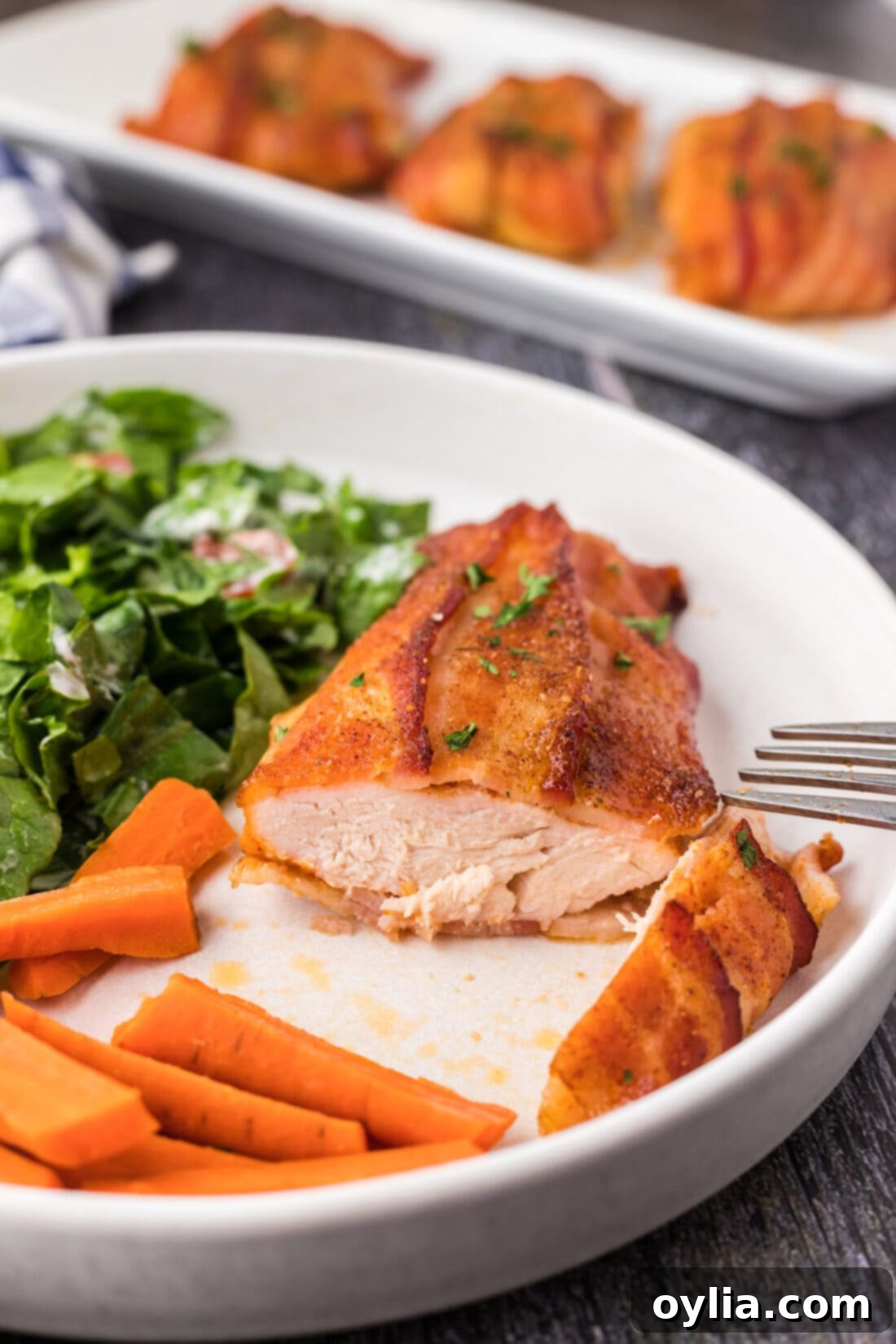 Slice of Bacon Wrapped Chicken on a plate, revealing its succulent, juicy interior