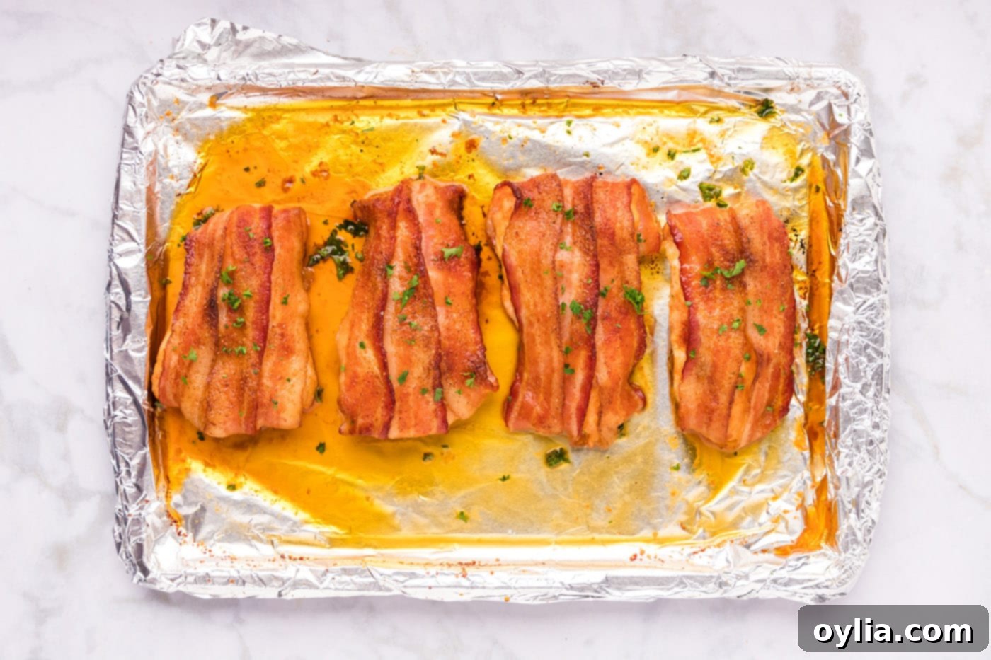 Freshly baked bacon wrapped chicken breasts on a baking sheet, golden and crispy, ready to be served