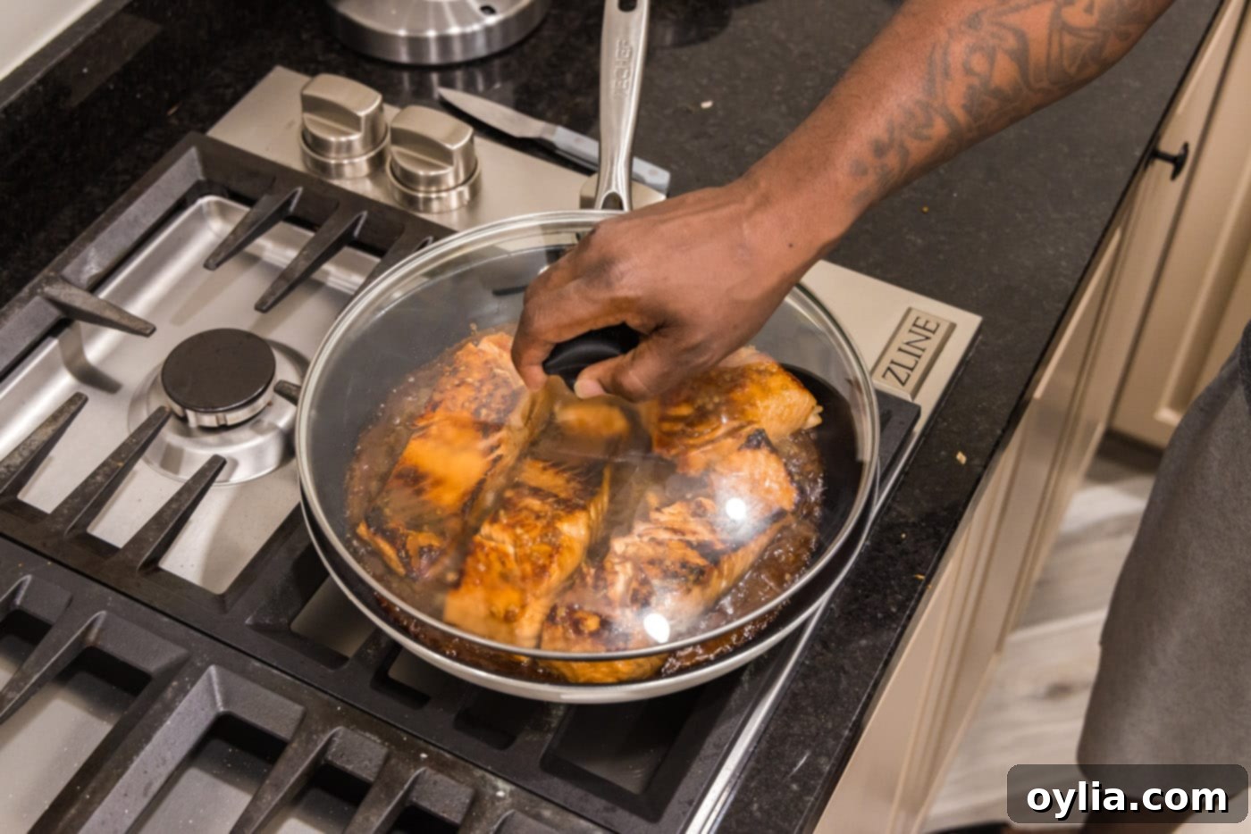 placing a lid on top of teriyaki salmon on the stovetop to simmer