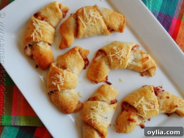 An overhead photo of pizza crescent roll ups on a white platter, perfectly golden brown and ready to serve.
