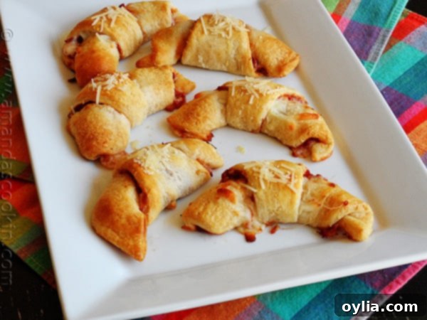 An overhead photo of pizza crescent roll ups on a white platter, showing all eight cooked roll ups.