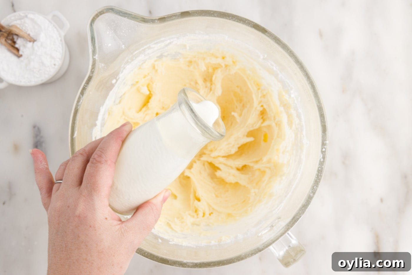 pouring heavy cream into cream cheese frosting
