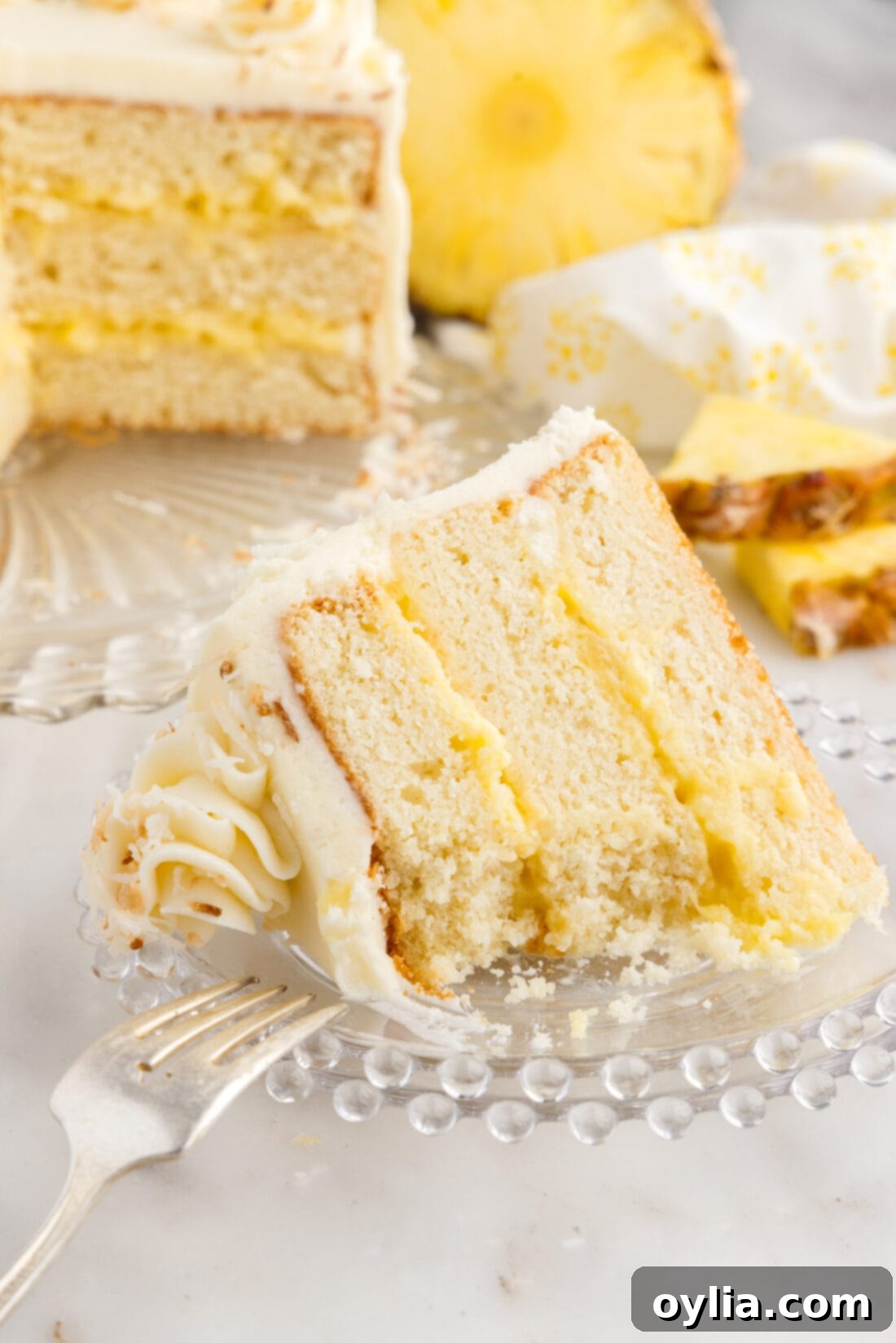 Partially eaten slice of Pineapple Coconut Cake on a plate with a fork