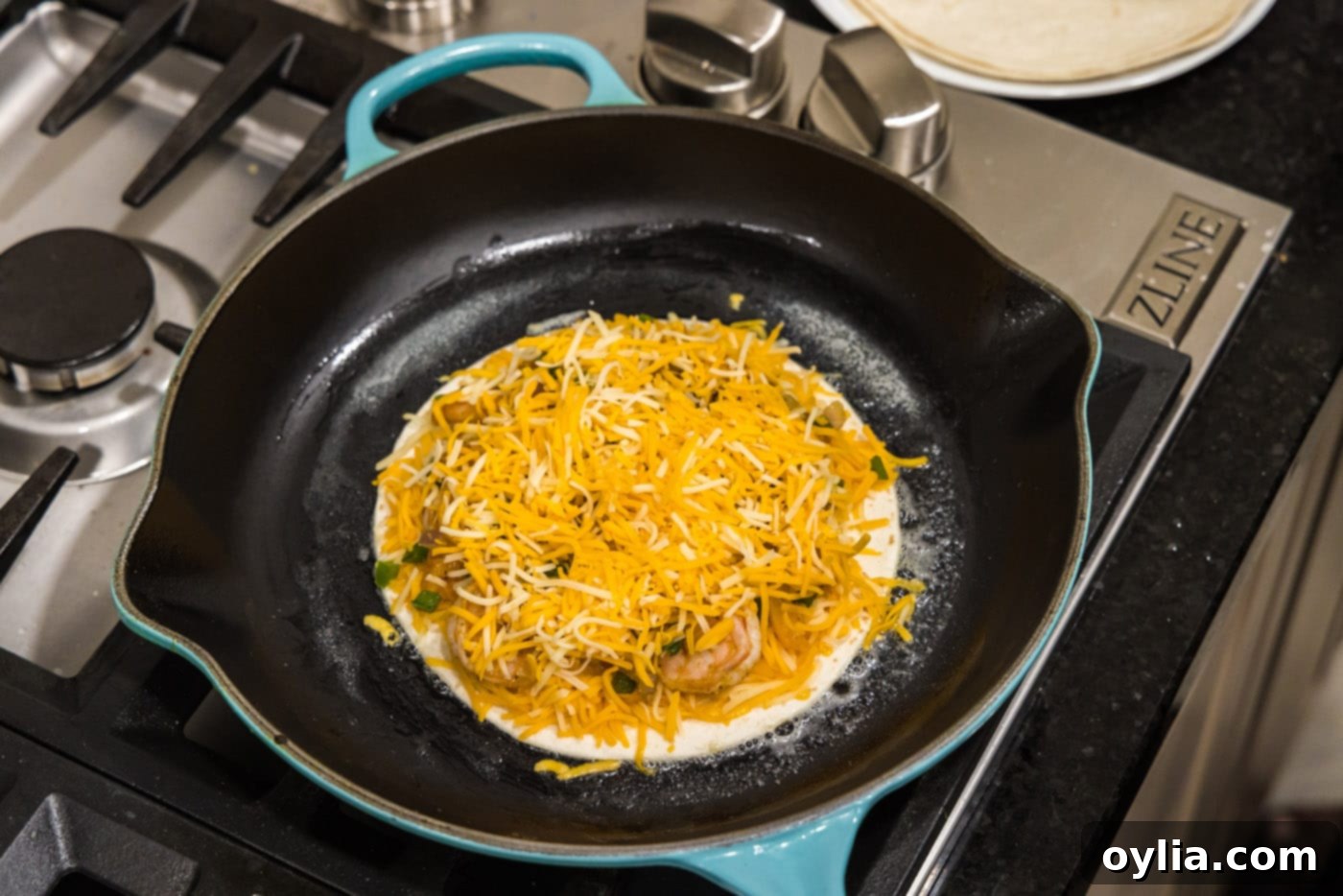 colby cheese on top of shrimp quesadilla ingredients in a skillet