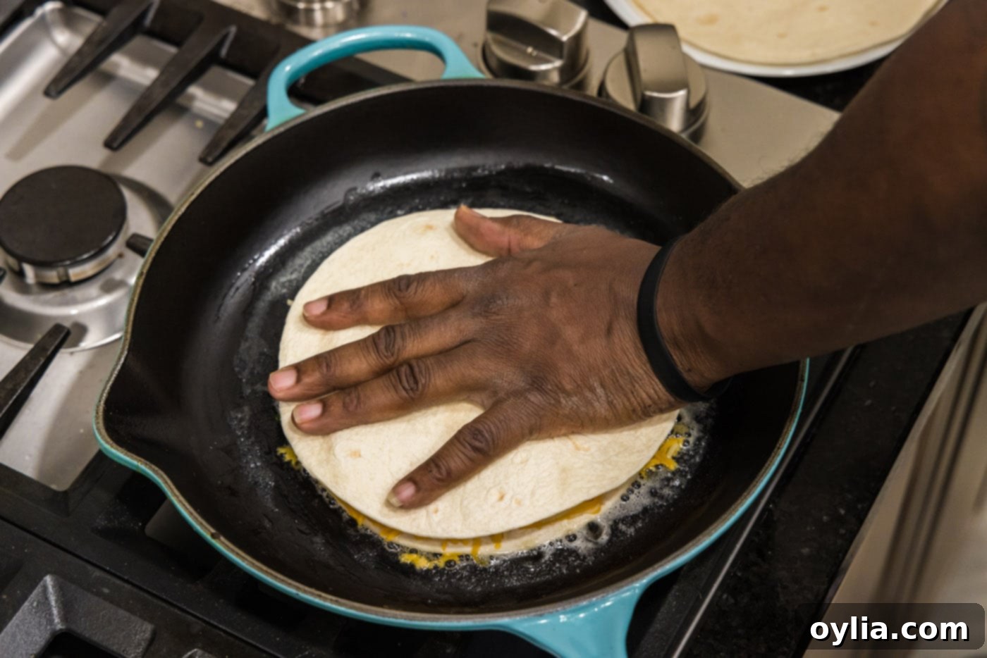 pressing a tortilla on top of cheese, shrimp, and veggies in a skillet