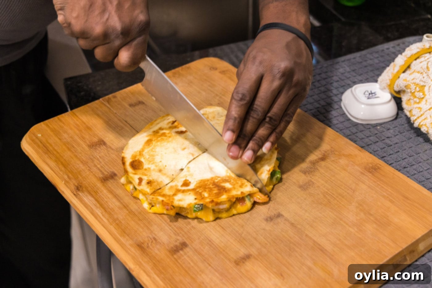 knife slicing shrimp quesadilla on a cutting board, ready to serve