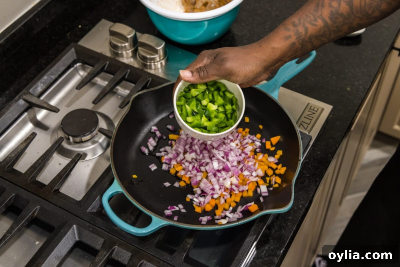 adding green bell pepper to skillet with red onion and orange bell pepper sautéing