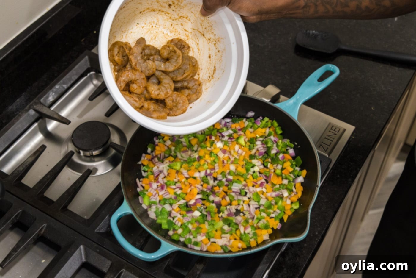 tossing seasoned shrimp into skillet with sauteed veggies