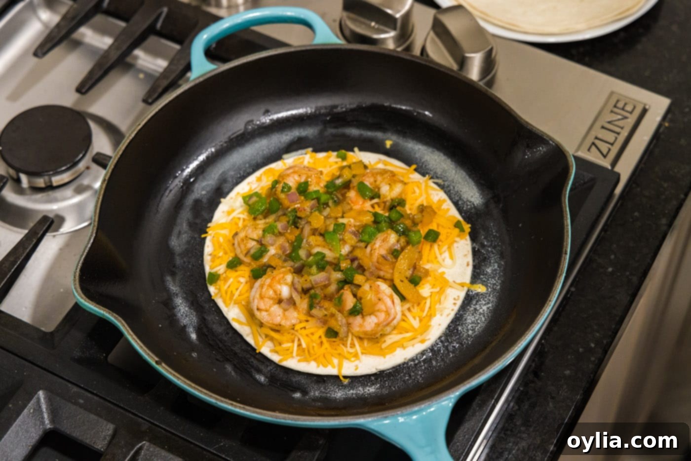 shrimp, cheese, and sauteed veggies being layered in a skillet