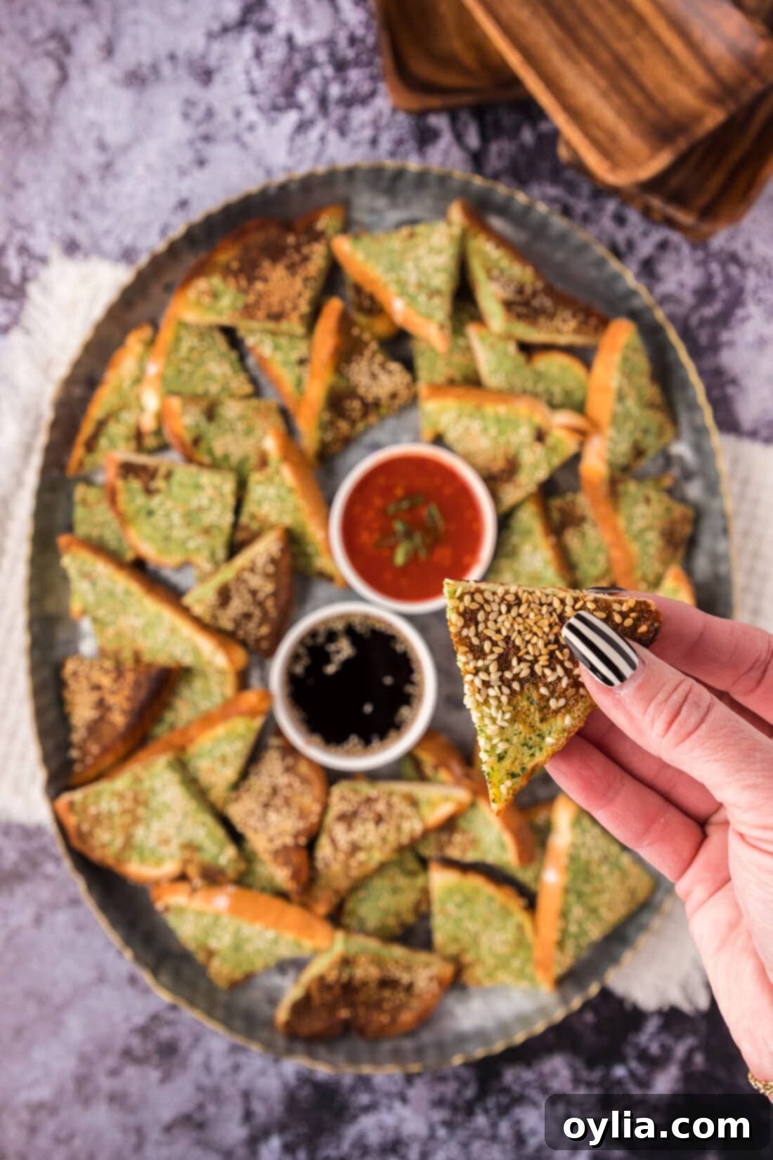 Irresistible Crispy Shrimp Toast 2 Shrimp Toast being held above a platter of Shrimp Toast