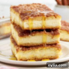 Stack of Sopapilla Cheesecake squares with honey drizzled on top