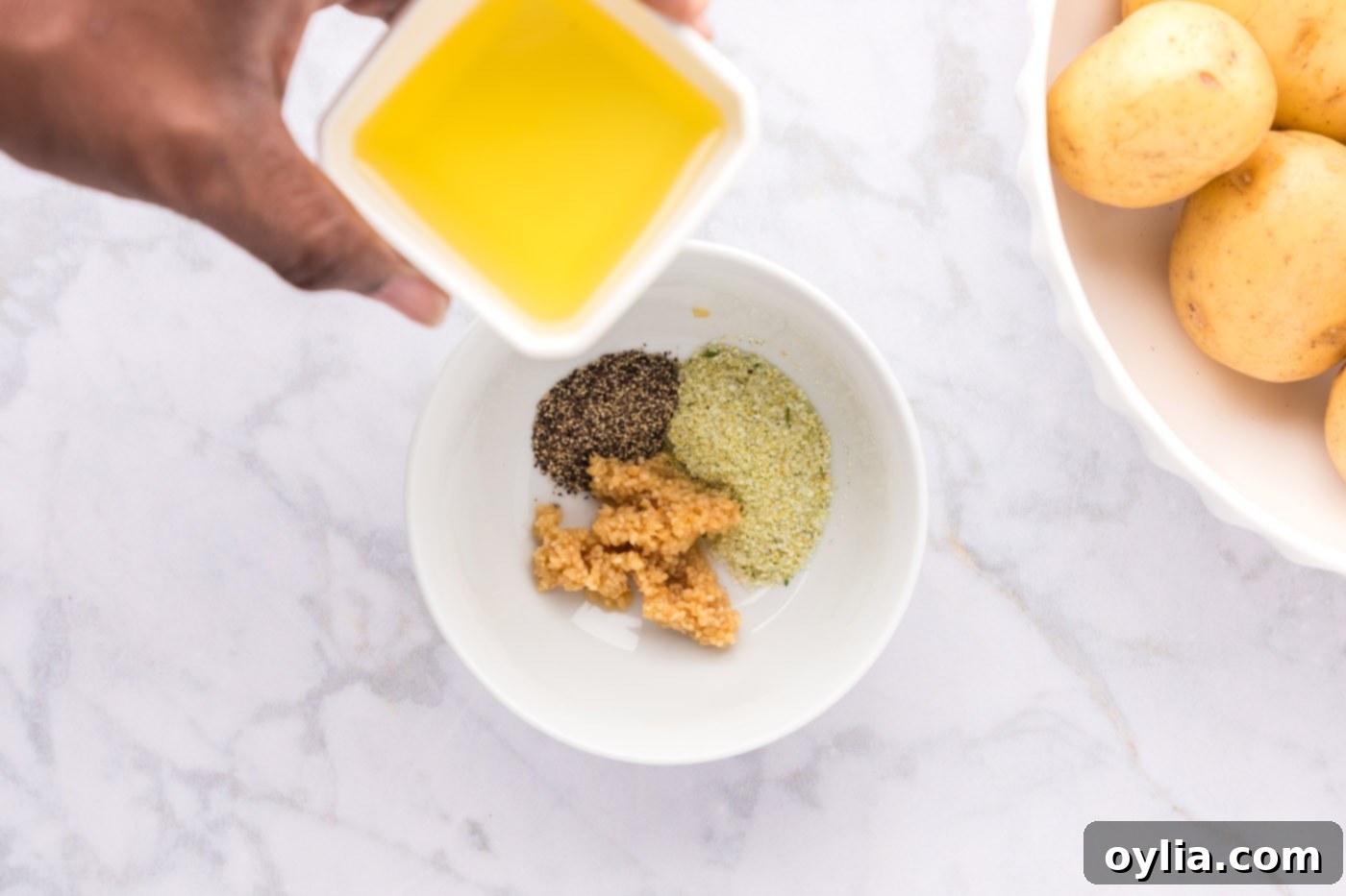adding olive oil to garlic and seasonings in bowl