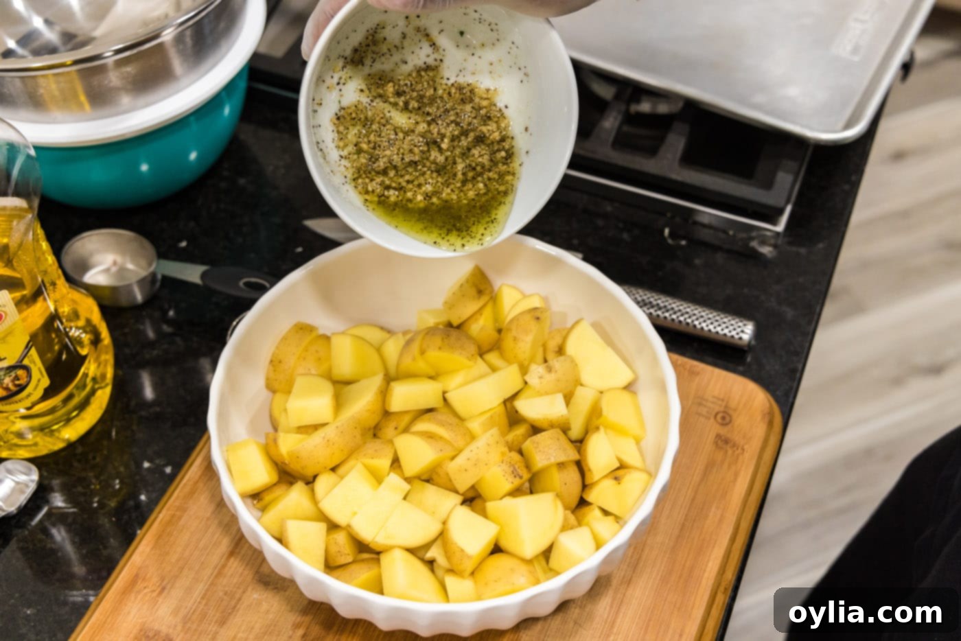 pouring garlic seasoned olive oil on top of potatoes