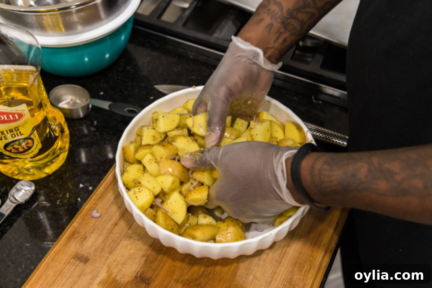 hands mixing cubed potatoes in a bowl