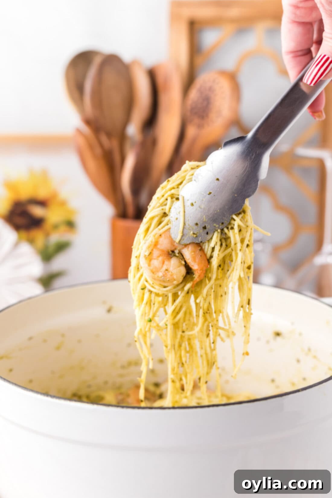 Fresh Pesto Shrimp Pasta 11 Tongs picking up a generous portion of Shrimp Pesto Pasta from a bowl
