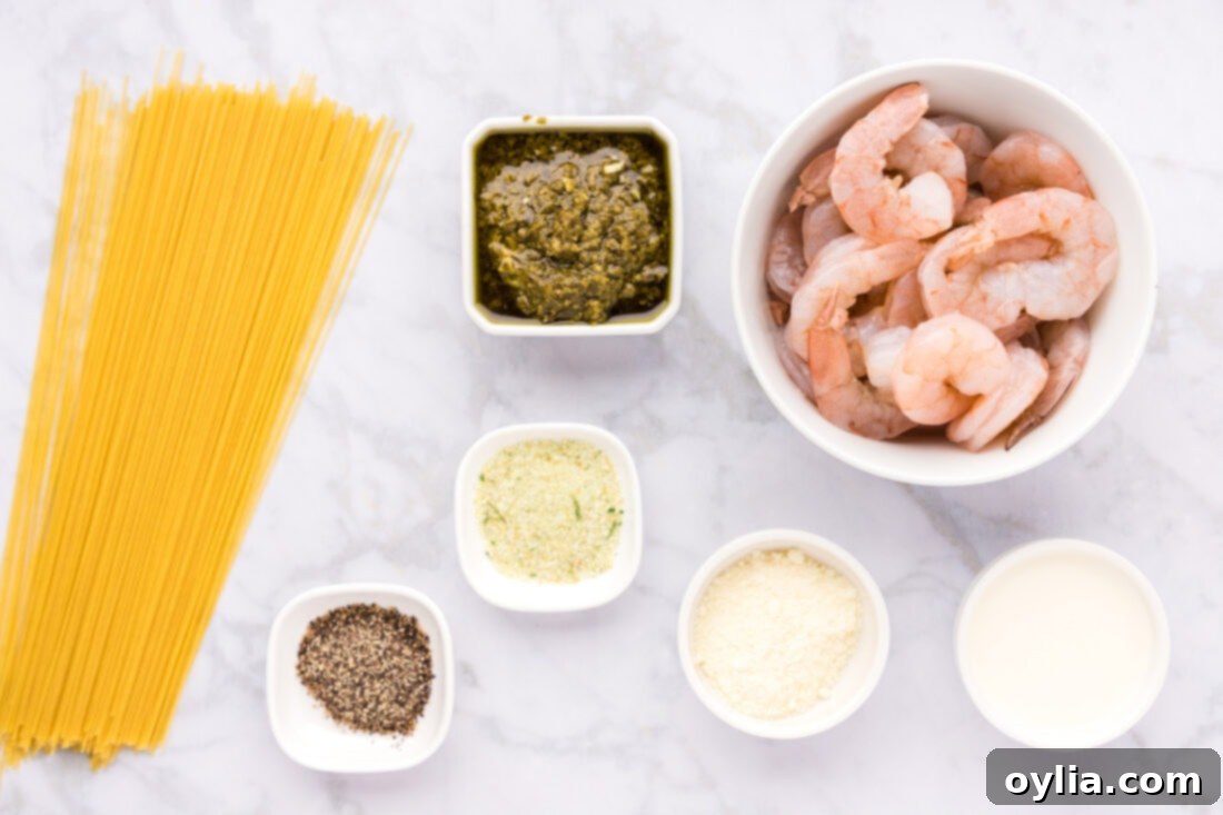 Fresh Pesto Shrimp Pasta 4 A flat lay photo showing all the ingredients laid out for Shrimp Pesto Pasta: shrimp, angel hair pasta, pesto, Parmesan, heavy cream, garlic salt, black pepper, and olive oil