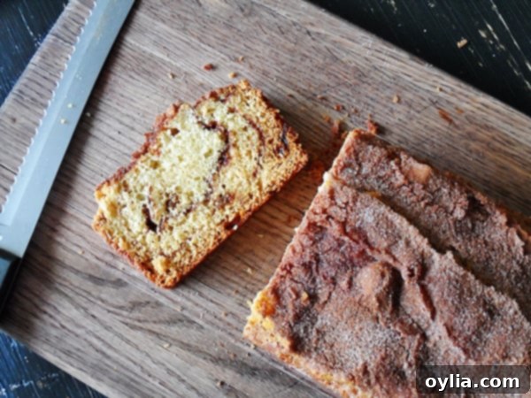 An overhead photo of a loaf of sliced cinnamon raisin swirl quick bread on a wooden cutting board, with individual slices ready to be enjoyed.