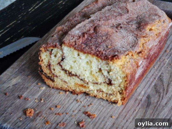A photo of a beautifully baked loaf of cinnamon raisin swirl quick bread on a wooden cutting board, ready to be sliced and served.