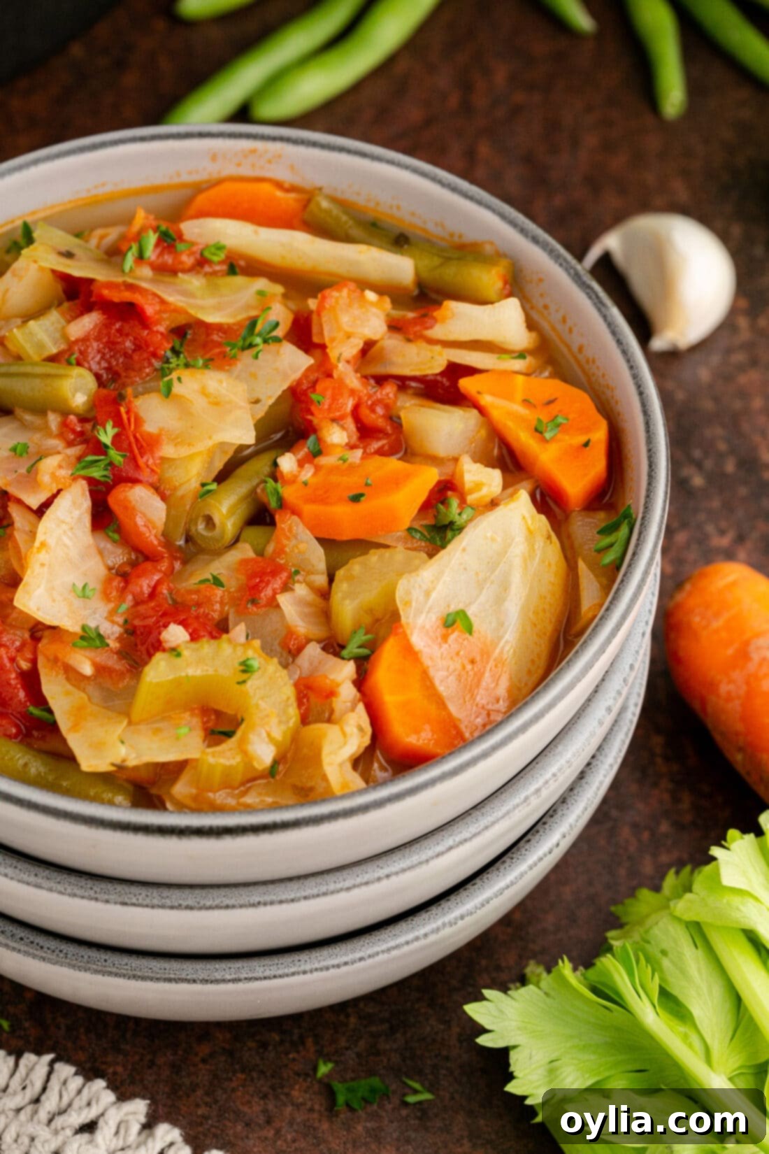 A close-up view of a vibrant bowl of Cabbage Soup, garnished with fresh parsley, highlighting its rich texture and steam.