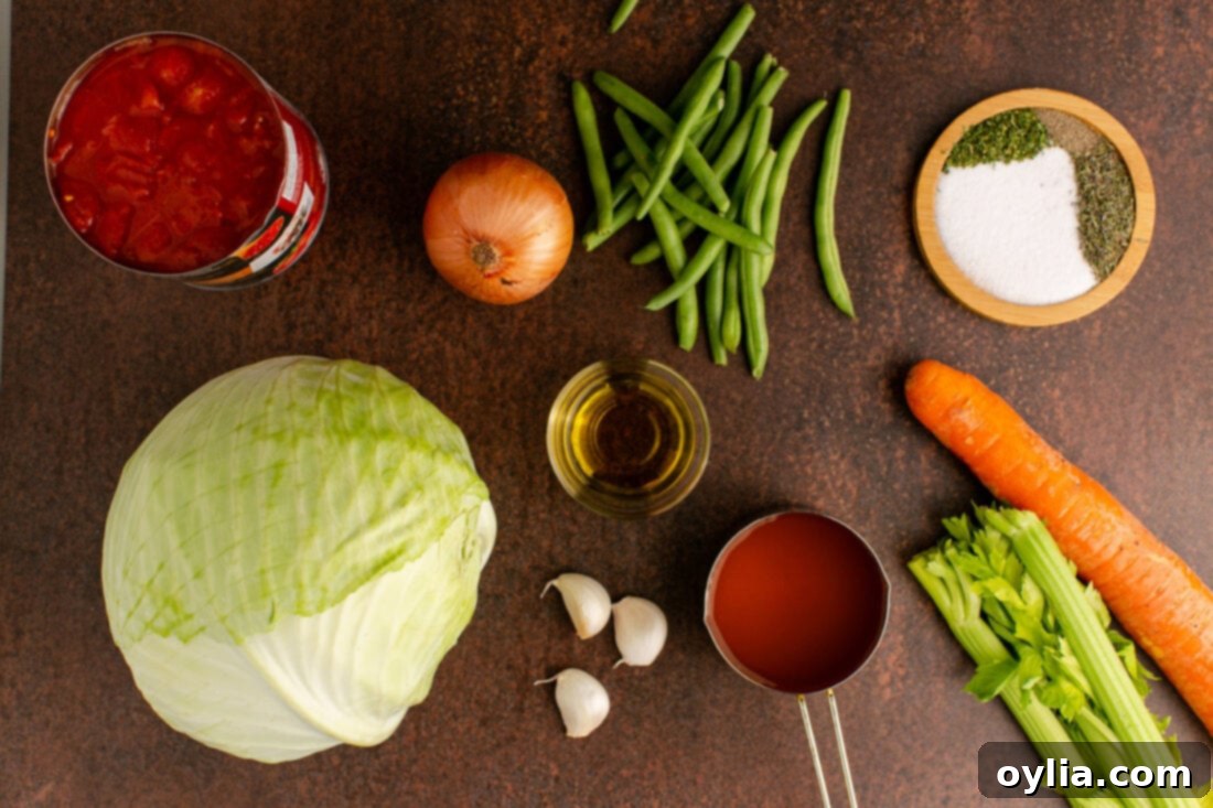 A vibrant selection of fresh ingredients laid out on a cutting board, including green cabbage, carrots, celery, onion, garlic, and green beans, ready for Cabbage Soup preparation.