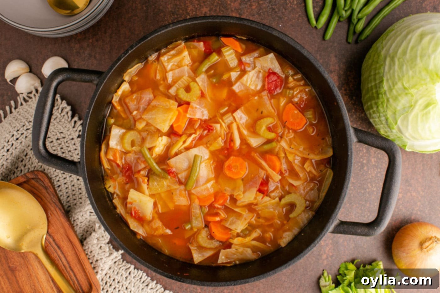 Cabbage soup simmering gently in a covered pot on the stovetop, releasing its aromatic steam.