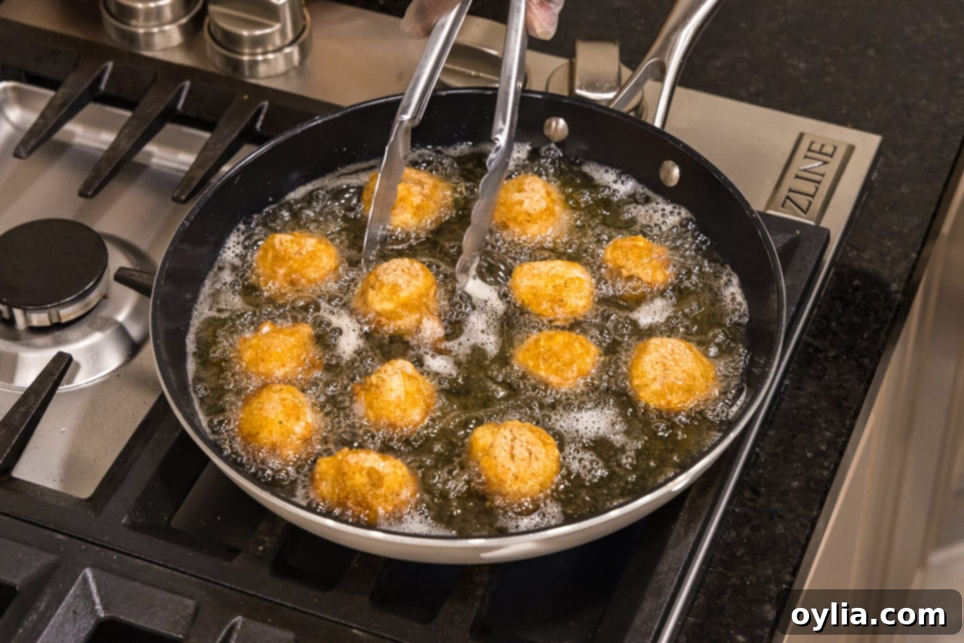 tongs turning scallops in a skillet of oil