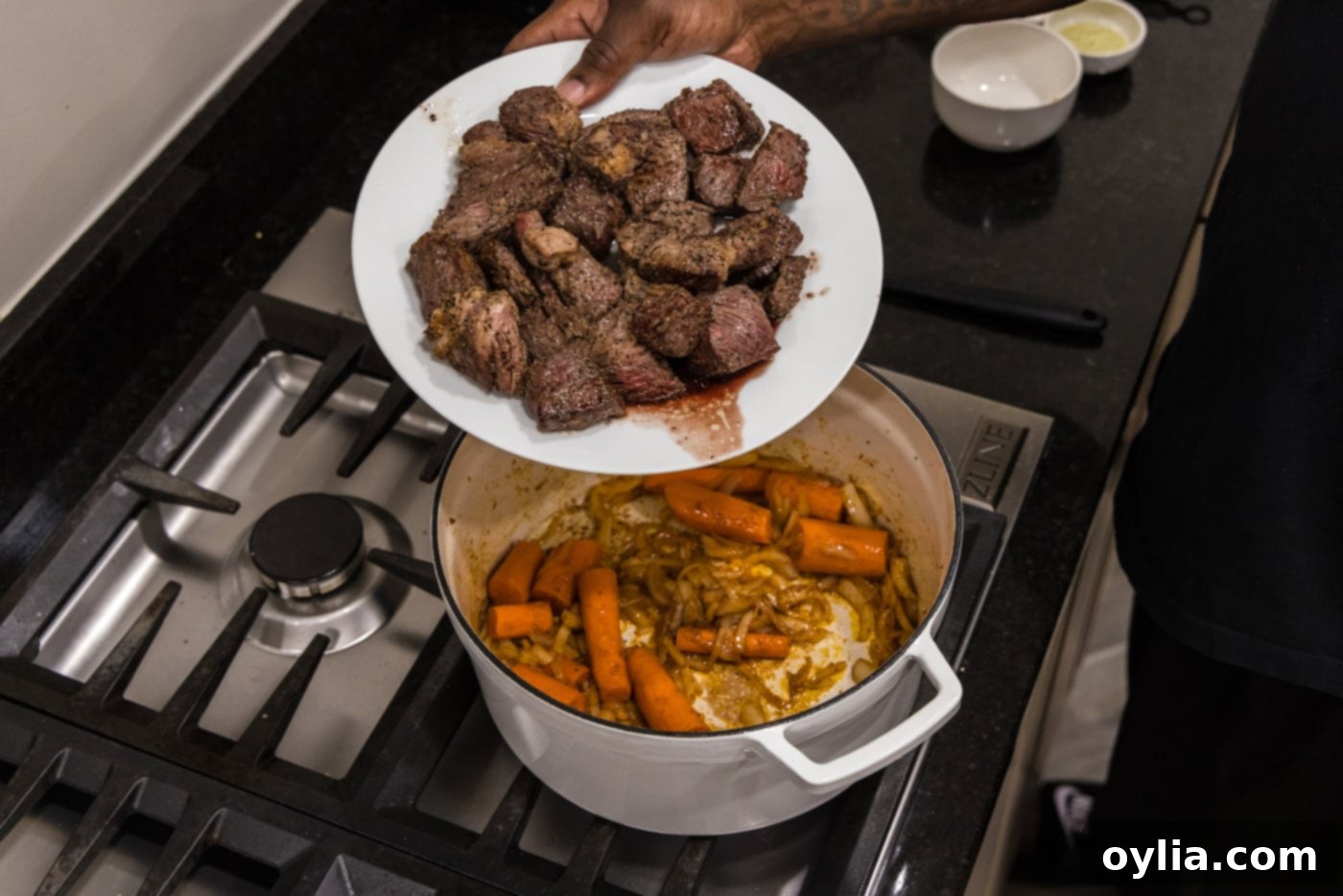 adding beef back to dutch oven with carrots and onions