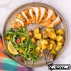 Overhead photo of Blackened Chicken on a plate with a salad, potatoes and a fork on the side
