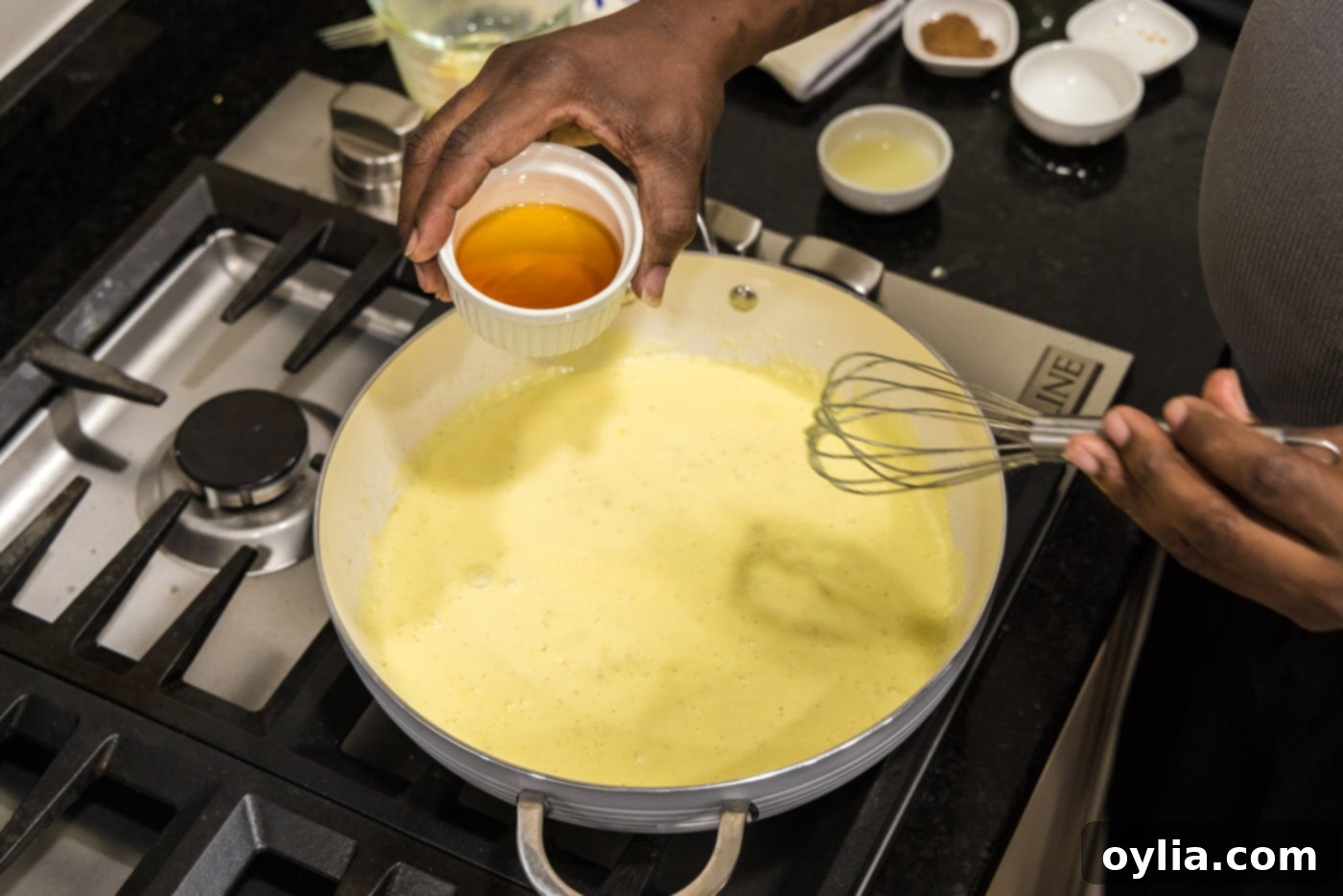 Adding Cognac to the simmering cream sauce in the skillet, enhancing the flavor profile.