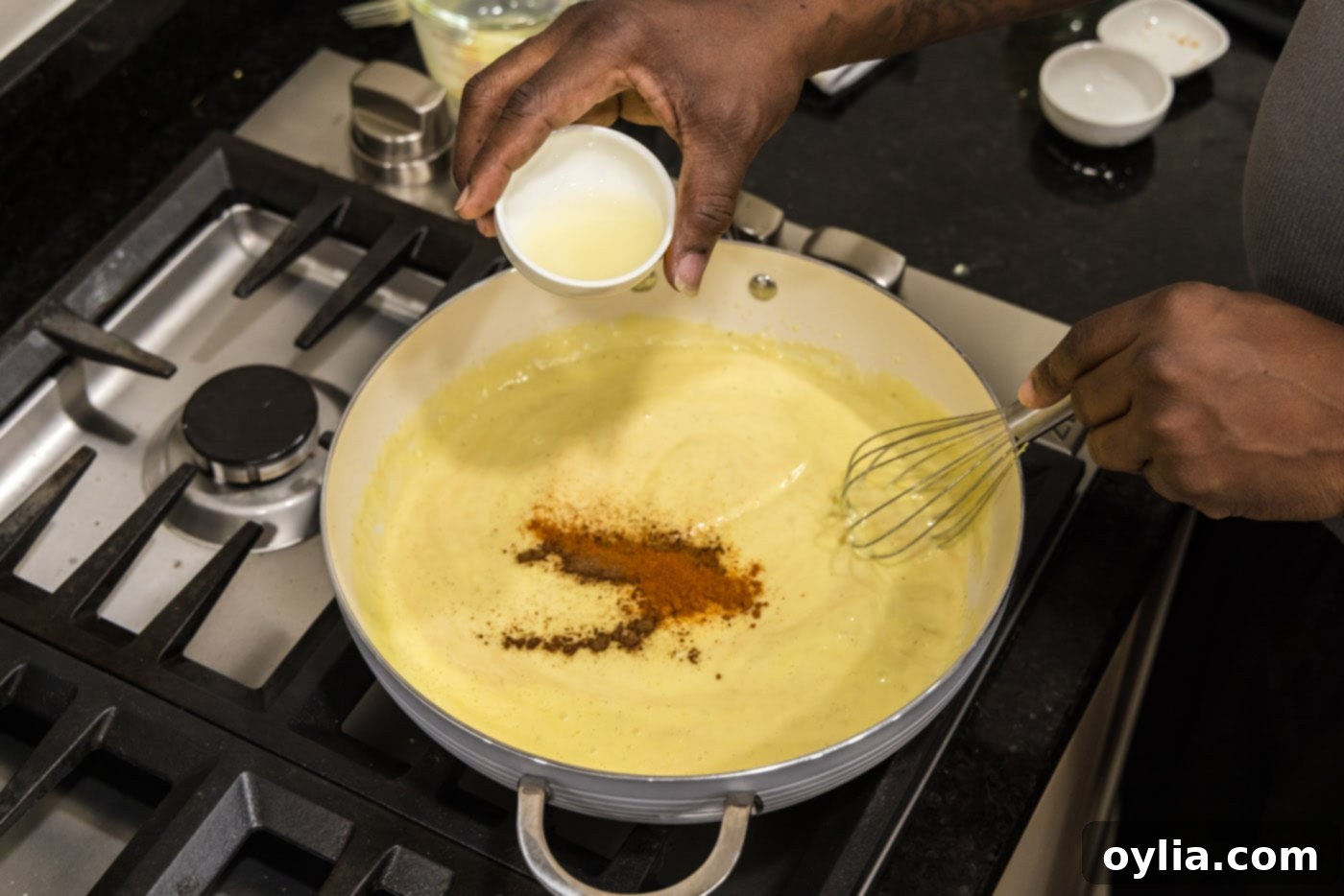 Adding fresh lemon juice to the creamy sauce mixture with seasonings in a skillet, balancing the rich flavors.