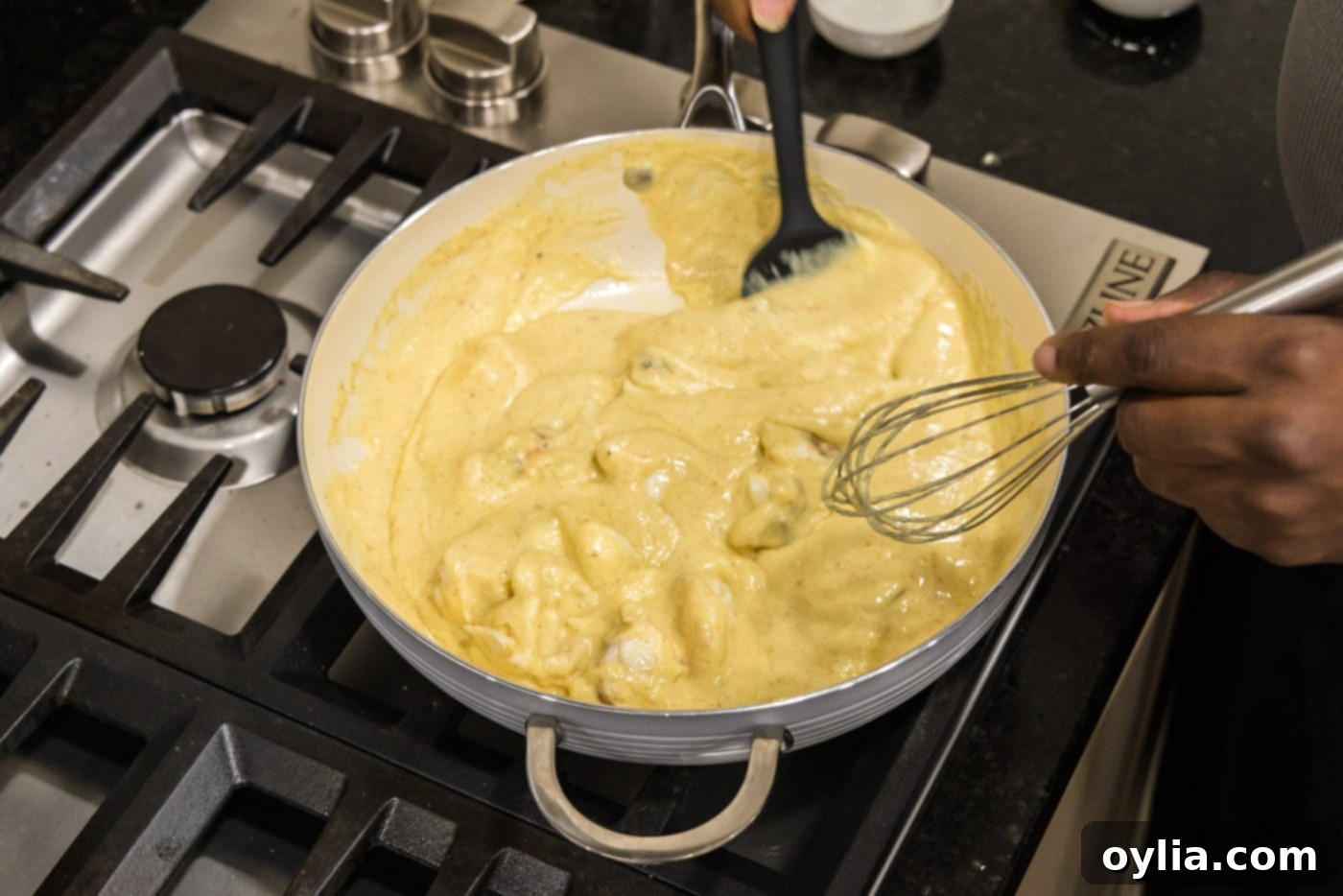 Mixing tender lobster chunks into the rich, creamy sauce for Lobster Newburg, ensuring every piece is coated.