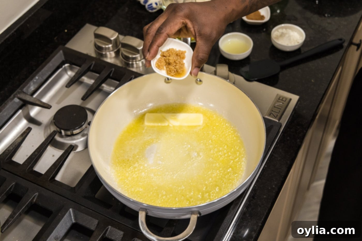 Adding minced garlic to melted butter in a skillet, the first step to building the rich sauce.