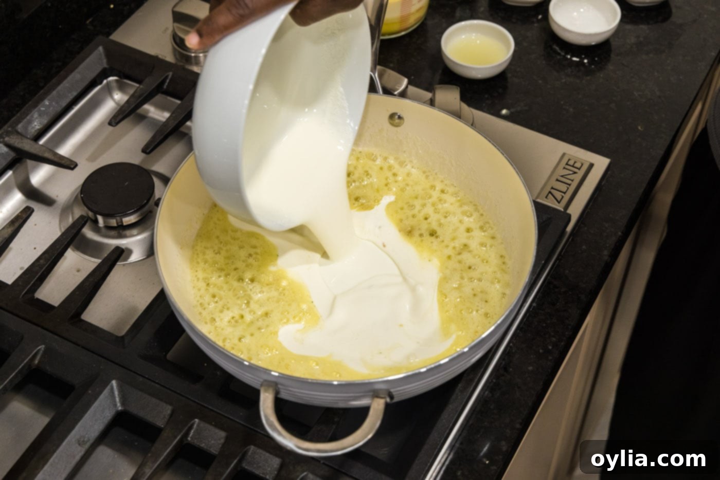 Pouring heavy cream into the skillet with the garlic butter mixture, creating the rich, creamy sauce base.