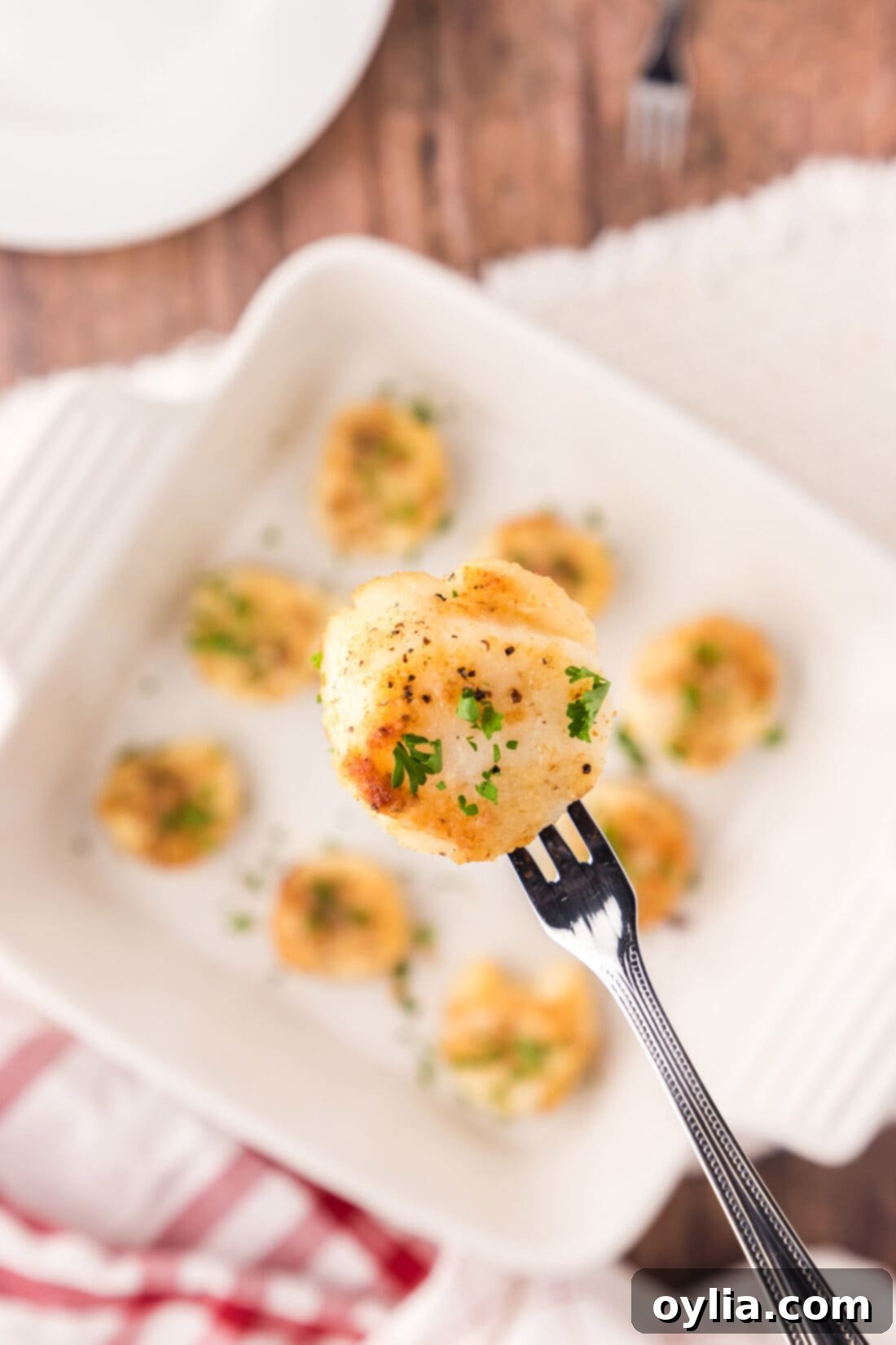 Close up of a golden-crusted baked scallop on a seafood fork