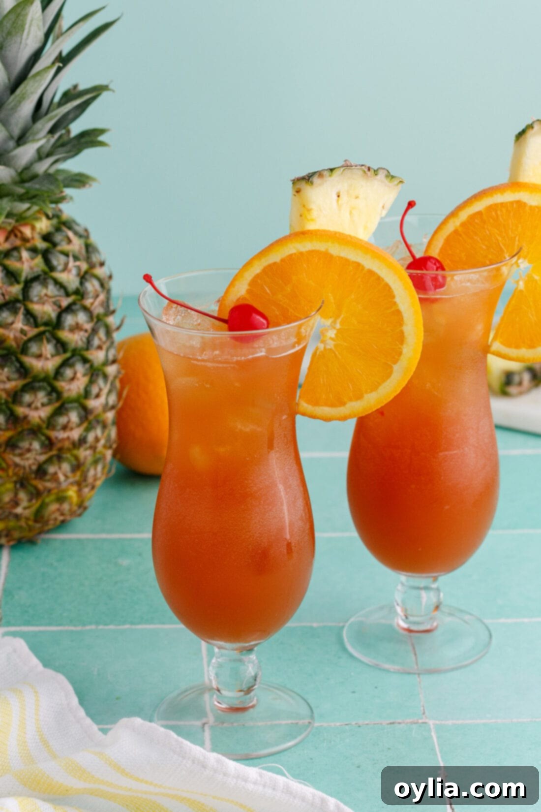 Two Rum Runners garnished with an orange wheel, pineapple wedge and cherry