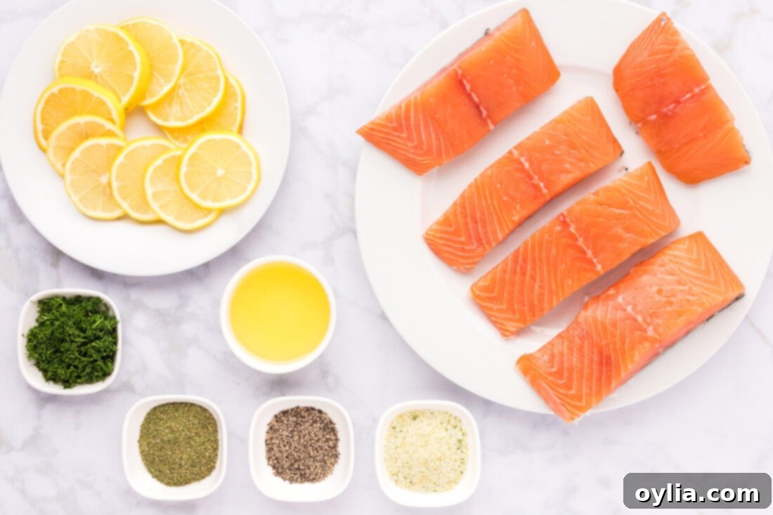 A flat lay photograph showcasing all the fresh ingredients needed for dill salmon: salmon fillets, fresh dill, lemon, olive oil, garlic salt, and black pepper.