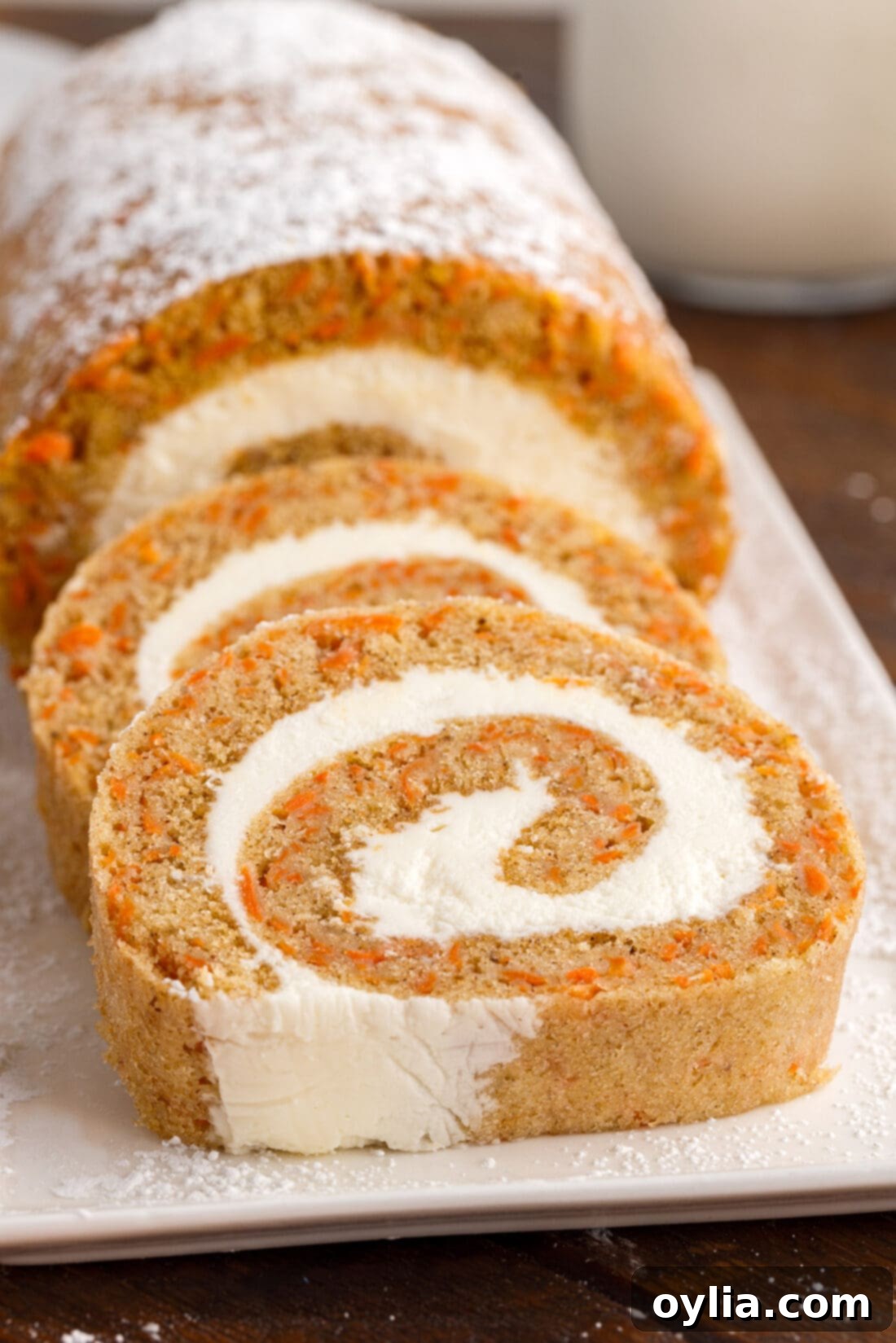 Carrot Cake Swiss Roll 20 Beautifully sliced Carrot Cake Roll pieces arranged artfully on a white serving platter, garnished with mint