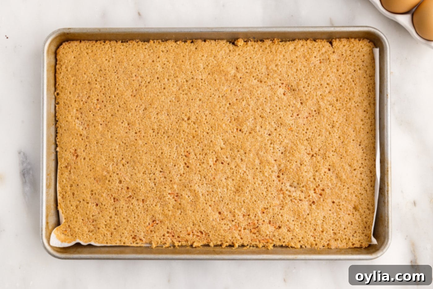 The baked carrot cake roll, golden brown and perfectly cooked in the jelly roll pan