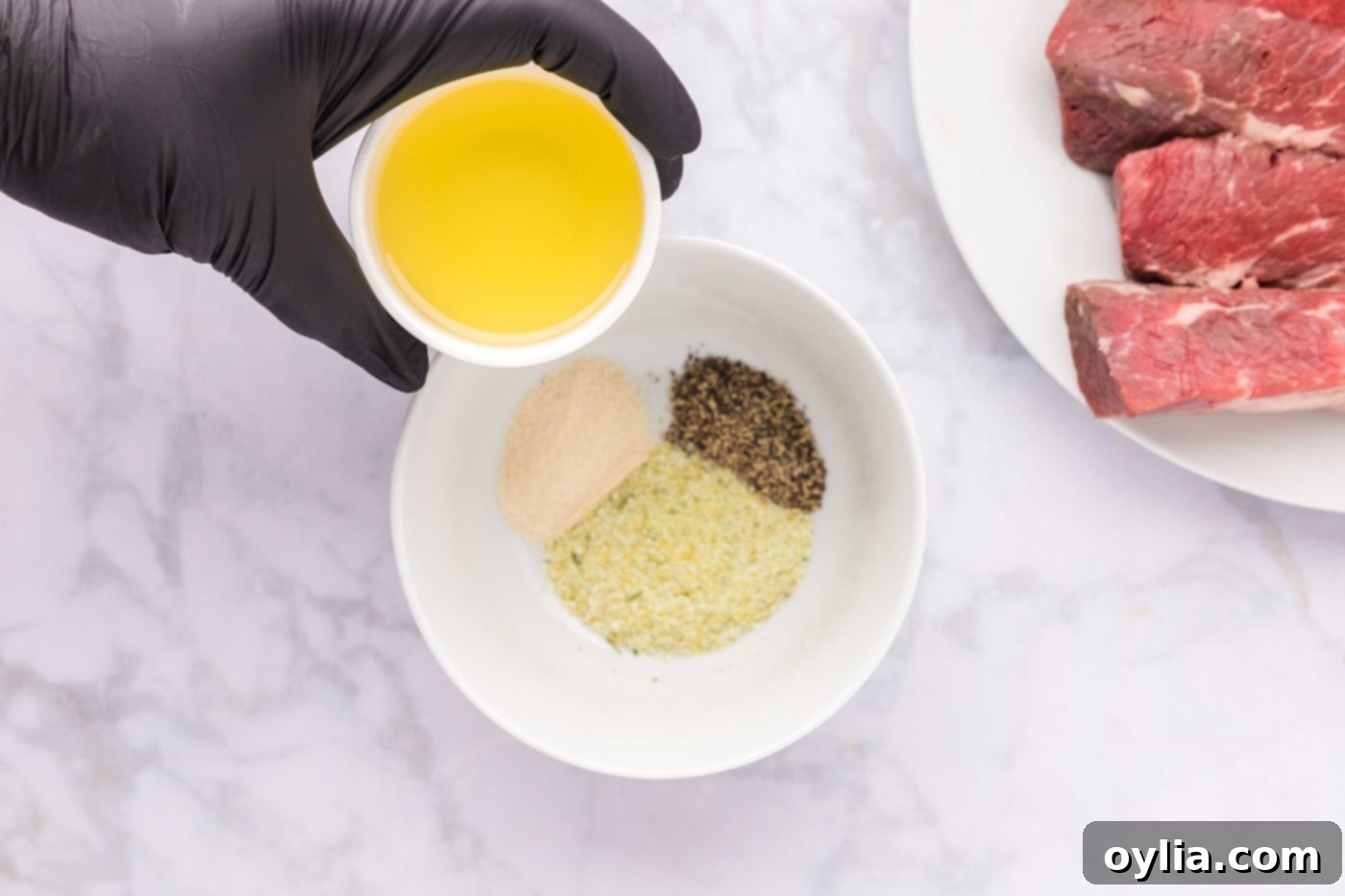 Applying olive oil and spices like garlic salt, pepper, and onion powder to boneless beef short ribs.