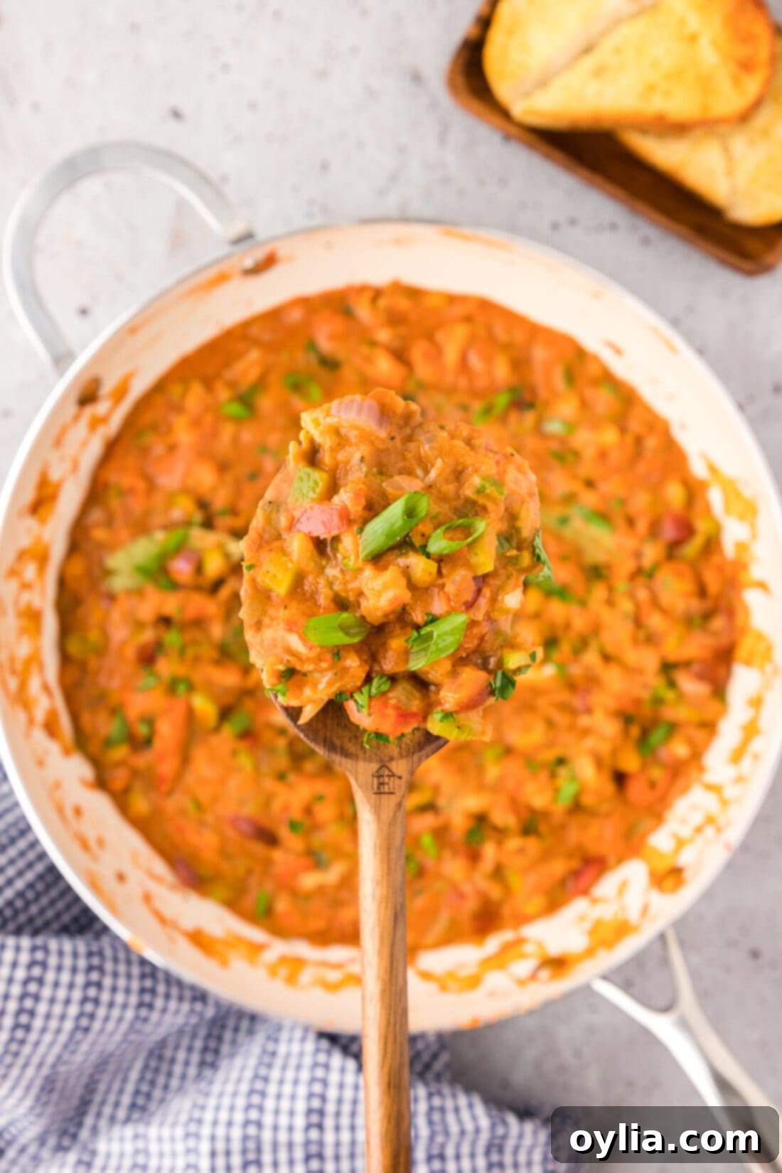 Spoonful of Crawfish Etoufee held above a skillet of Crawfish Etoufee, showing the rich sauce and crawfish meat.