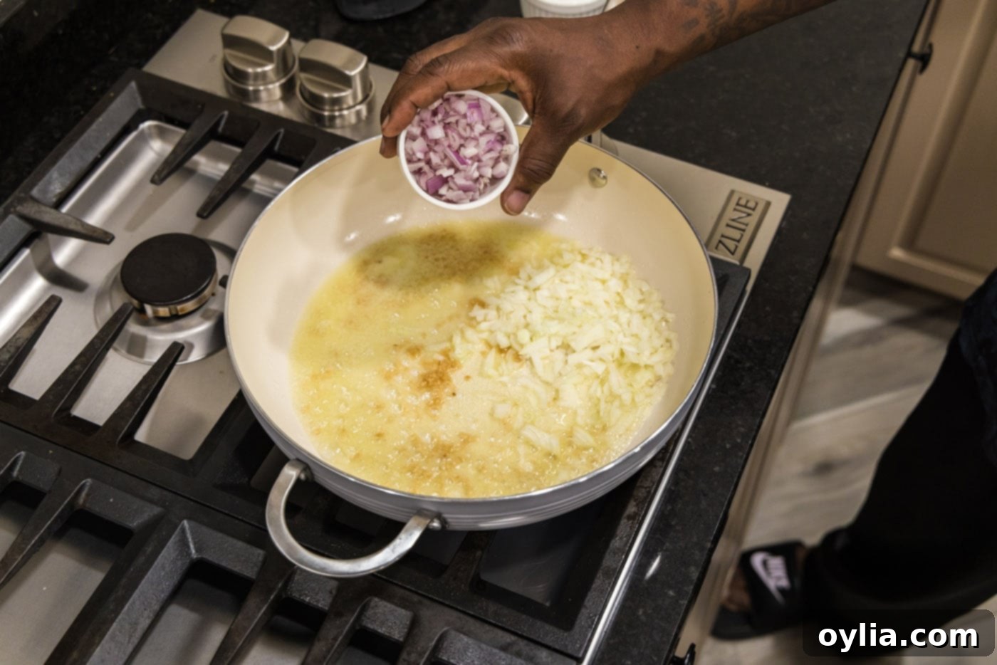 adding shallots to skillet with onion and garlic with oil, starting the aromatic base for etouffee
