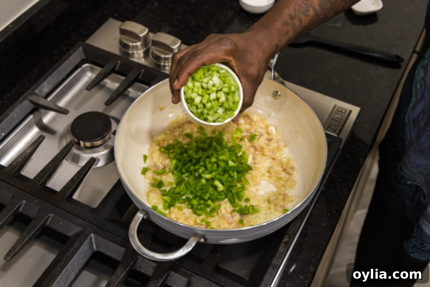 adding celery to roux with bell pepper in a skillet, contributing to the holy trinity