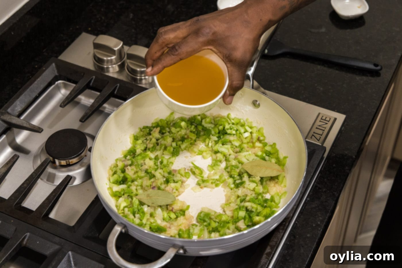 adding chicken stock to skillet of holy trinity vegetables to form the sauce base