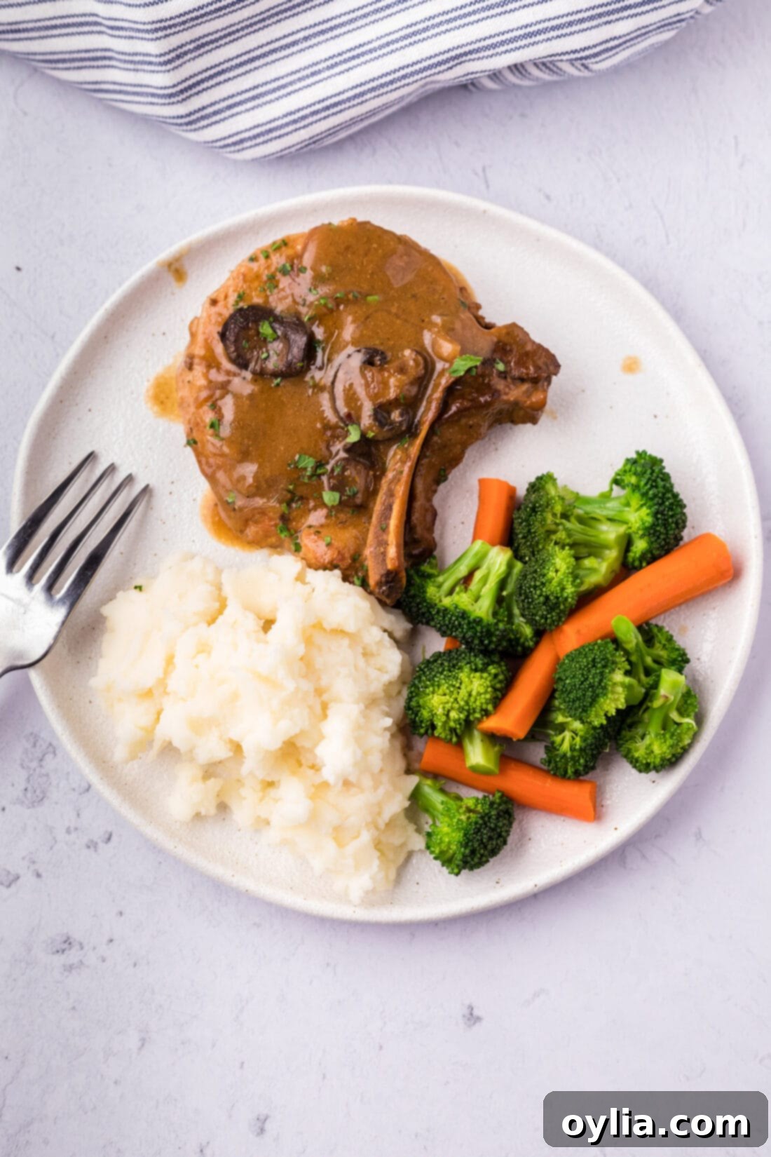 Crockpot Pork Chop served on a plate with mashed potatoes and mixed vegetables