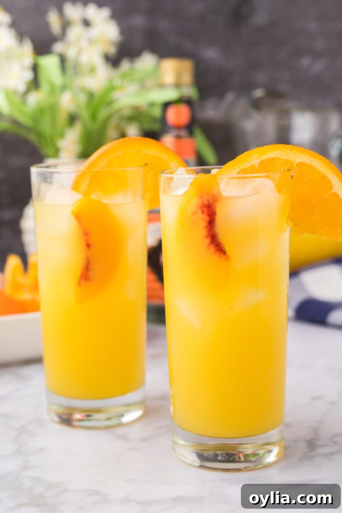 Close up photo of two Fuzzy Navels with orange and peach garnishes.