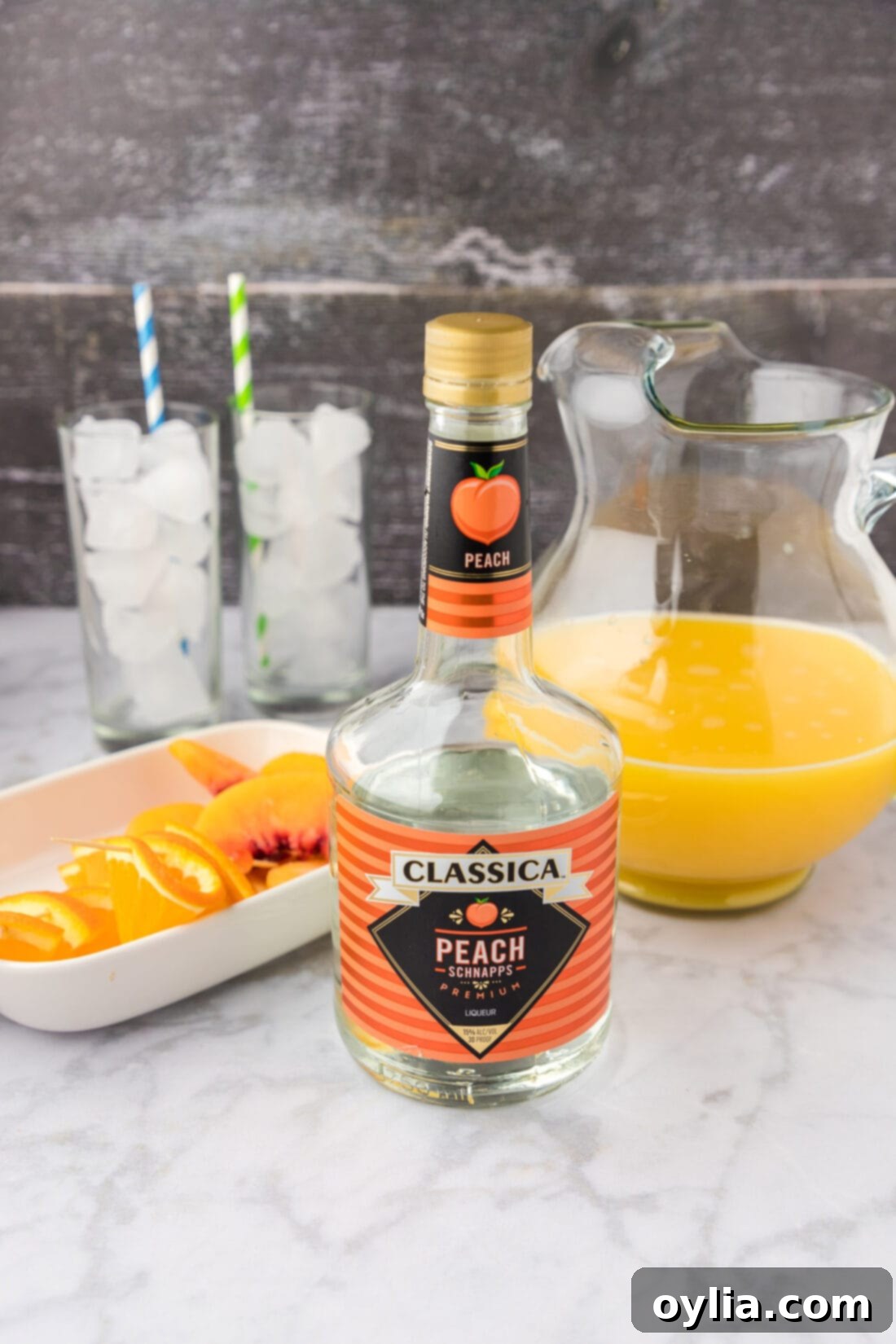 Ingredients for Fuzzy Navel laid out: peach schnapps, orange juice, and a glass with ice.
