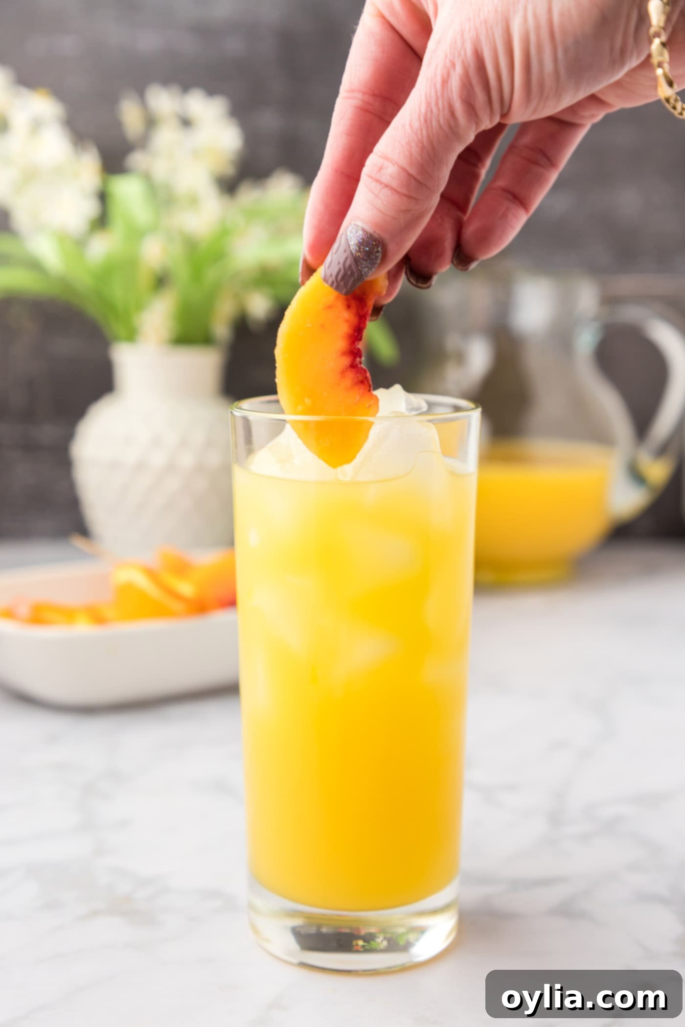 adding frozen peach slices to fuzzy navel cocktail