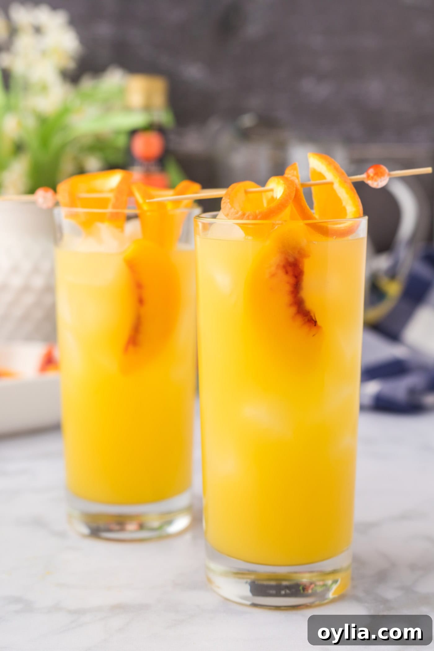 fuzzy navel cocktail with skewered orange slices and peach slices